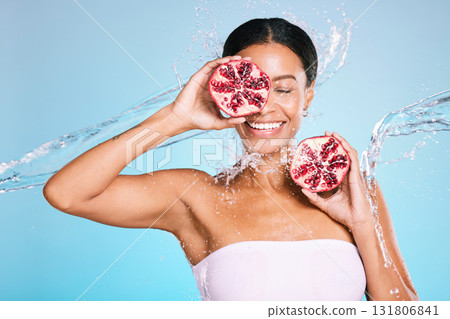 Skincare, beauty and woman with a pomegranate for healthy food and skin on a blue background. Face of aesthetic model person with water splash and fruit for sustainable facial health and wellness Skincare, beauty and woman with a pomegranate for healthy food and skin on a blue background. Face of aesthetic model person with water splash and fruit for sustainable facial health and wellness 131806841
