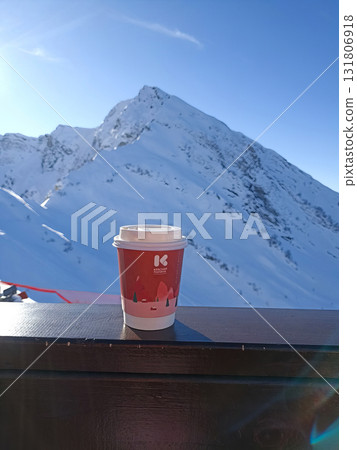 A red cup with a white lid sits on a wooden railing 131806918
