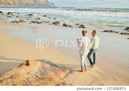 Beach, love and a senior couple walking on the sand by the ocean or sea for romance or dating at sunset. Nature, summer or back with a mature woman and man taking romantic walk together on the coast 131806953