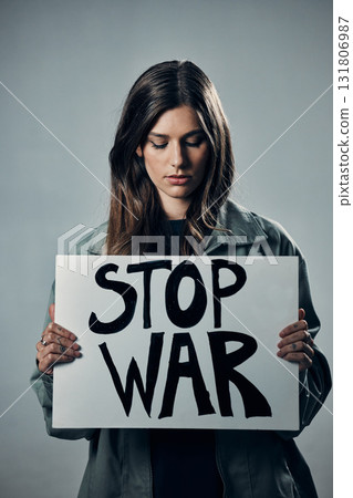 War, stop and sad woman with a sign as a voice isolated on a grey studio background. Protest, crime and girl with a board against conflict, violence and danger with an opinion in Russia on a backdrop War, stop and sad woman with a sign as a voice isolated on a grey studio background. Protest, crime and girl with a board against conflict, violence and danger with an opinion in Russia on a backdrop 131806987