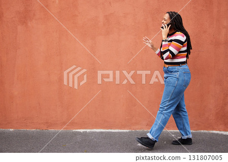Mockup, phone call and black woman in a city street against orange background for advertising. Walking, talking and girl speaking on copy space outdoor for relax, trip and social network on space 131807005