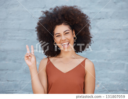 Happy woman, portrait smile and afro with peace sign against a gray wall background. Excited or friendly female face smiling showing peaceful hand emoji or gesture with fun positive attitude Happy woman, portrait smile and afro with peace sign against a gray wall background. Excited or friendly female face smiling showing peaceful hand emoji or gesture with fun positive attitude 131807059