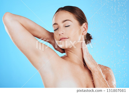 Beauty, shower and woman in a studio with a wellness, health and self care body routine. Skincare, water and female model washing while doing a luxury skin treatment isolated by a blue background. 131807081