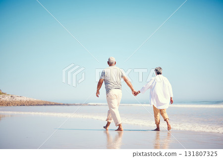 Holding hands, beach and an old couple walking outdoor in summer with blue sky mockup from behind. Love, romance or mock up with a senior man and woman taking a walk on the sand by the ocean or sea Holding hands, beach and an old couple walking outdoor in summer with blue sky mockup from behind. Love, romance or mock up with a senior man and woman taking a walk on the sand by the ocean or sea 131807325
