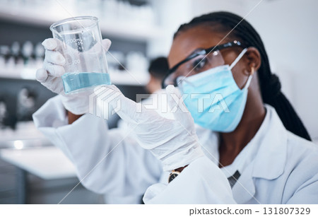 Science, covid and liquid with a black woman doctor working in a laboratory for research or innovation. Medical, analytics and development with a female scientist at work in a lab for chemistry 131807329