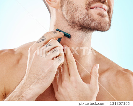 Hands, shaving and beard with a man grooming in studio on a blue background for skincare or hygiene. Shave, tattoo and neck with a male in the bathroom for hair removal as part of a morning routine Hands, shaving and beard with a man grooming in studio on a blue background for skincare or hygiene. Shave, tattoo and neck with a male in the bathroom for hair removal as part of a morning routine 131807365
