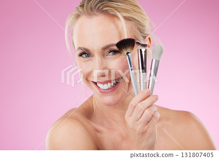 Portrait, makeup and brushes with a mature woman in studio on a pink background to promote a cosmetic product. Face, happy and cosmetics with an attractive older female posing for beauty treatment Portrait, makeup and brushes with a mature woman in studio on a pink background to promote a cosmetic product. Face, happy and cosmetics with an attractive older female posing for beauty treatment 131807405
