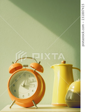 Vintage Orange Alarm Clock and Colorful Kitchenware on a Sunny Tabletop 131807415