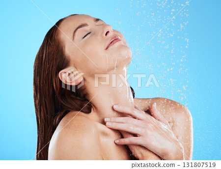 Water splash, shower and woman washing as body care, skincare and self care isolated in a studio blue background. Aqua, beauty and female model cleaning her skin as wellness feeling calm and relaxed 131807519
