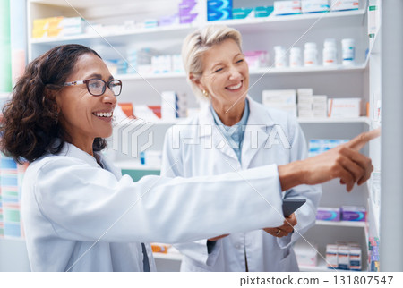 Pharmacy women, shelf and pointing together with smile, stock and product for medical wellness in store. Pharmacist training, management and teamwork for medicine, service and healthcare in shop 131807547
