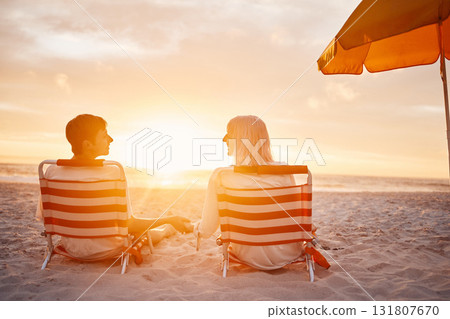 Beach, back and couple holding hands during the sunset for support during a date on valentines day. Travel, relax and man and woman with affection, trust and conversation sitting by the ocean Beach, back and couple holding hands during the sunset for support during a date on valentines day. Travel, relax and man and woman with affection, trust and conversation sitting by the ocean 131807670