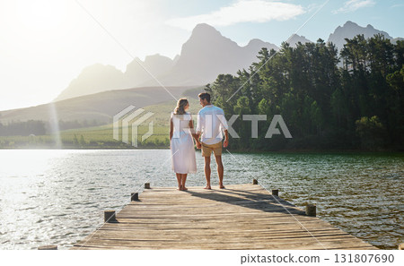 Love, couple and holding hands at lake, smile and bonding outdoors on vacation sunrise. Romance date, care and happy man and woman with trust, support or affection for romantic holiday at creek pier Love, couple and holding hands at lake, smile and bonding outdoors on vacation sunrise. Romance date, care and happy man and woman with trust, support or affection for romantic holiday at creek pier 131807690