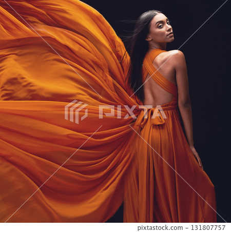 Fashion, woman and elegant, dress flying and style, beauty on dark background, portrait and model in orange in studio. Indian female, glamour and stylish with sexy person, luxury and designer wear Fashion, woman and elegant, dress flying and style, beauty on dark background, portrait and model in orange in studio. Indian female, glamour and stylish with sexy person, luxury and designer wear 131807757