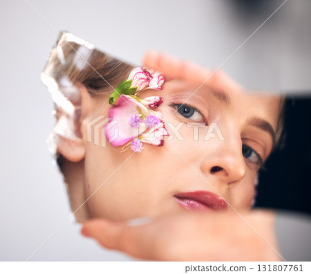 Portrait, skincare and woman with reflection, flower and cosmetics on grey studio background. Face, female and lady with mirror, plants and floral for decoration, makeup and natural dermatology 131807761