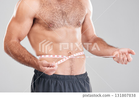Health, diet and man with measuring tape on stomach, healthy exercise weight loss and body care. Sports, nutrition and fitness, tracking weightloss and six pack progress isolated on grey background. 131807838
