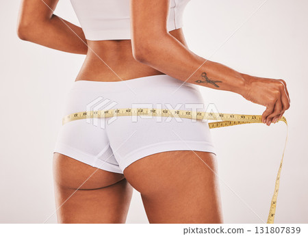 Measure, lose weight or woman with tape for butt or body goals in studio isolated on white background. Fitness, healthcare or healthy girl measuring buttocks for goal progress, training or motivation 131807839