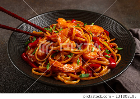 udon stir-fry shrimp noodles with red bell pepper and green onion, served in a black bowl, with chopsticks, dark background, udon stir-fry shrimp noodles with red bell pepper and green onion, served in a black bowl, with chopsticks, dark background, 131808193