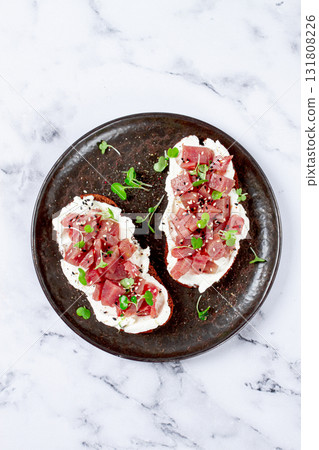 sandwiches, rye bread with cream cheese, sliced tuna fillet with herbs, breakfast on a black plate, homemade, 131808226