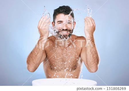 Water splash, skin care and portrait of man for clean spa facial for beauty hygiene and dermatology. Aesthetic model person washing face on blue background for cosmetics, body and detox cleaning Water splash, skin care and portrait of man for clean spa facial for beauty hygiene and dermatology. Aesthetic model person washing face on blue background for cosmetics, body and detox cleaning 131808269