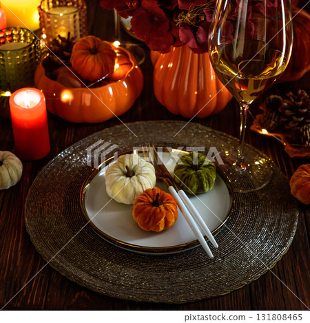 Thanksgiving table setting with decorative pumpkins, candles and string lights on dark wooden table Thanksgiving table setting with decorative pumpkins, candles and string lights on dark wooden table 131808465