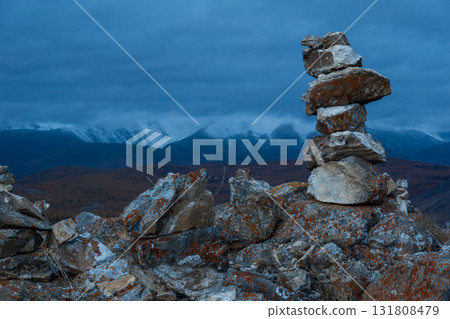 Stacked rocks on a windy mountain ridge with snow capped peaks in distant valley Stacked rocks on a windy mountain ridge with snow capped peaks in distant valley 131808479