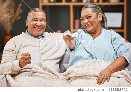 Coffee, relax and old couple watching tv with blanket on sofa in home living room laughing at comic film. Retirement portrait, valentines love and happy elderly man and woman streaming on television. Coffee, relax and old couple watching tv with blanket on sofa in home living room laughing at comic film. Retirement portrait, valentines love and happy elderly man and woman streaming on television. 131808731