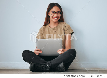 Portrait, smile and student woman with laptop in home for studying, learning or education. Technology, computer and happy female sitting on floor with pc for research on wall background for mockup. 131808790
