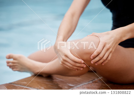 Hands, knee injury and swimming pool with a woman holding her joint in pain after a sports workout. Fitness, water and anatomy with a female swimmer suffering from an injured leg during exercise 131808822