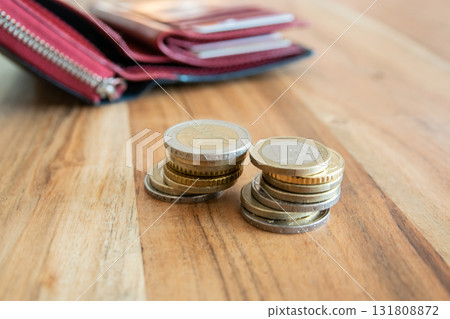 Coins stack on the wood table near the black leather partmone. Wallet with european money for commerce business concept. Coins stack on the wood table near the black leather partmone. Wallet with european money for commerce business concept. 131808872