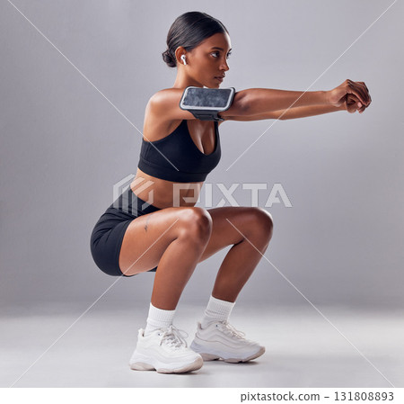 Black woman, studio background and squat training for fitness, smartphone and strong legs, muscle or mind. Gen z girl, personal trainer and phone with vision, motivation or mindset for anatomy goal 131808893