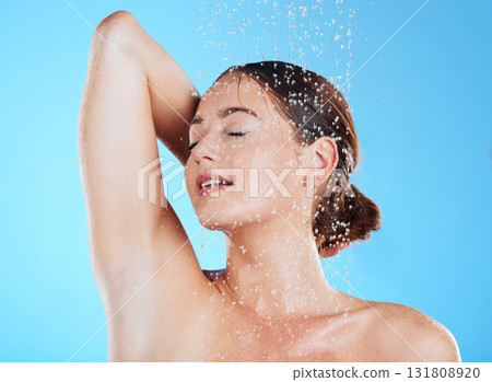 Water, shower and woman cleaning her body as skincare, dermatology and self care isolated in a studio blue background. Aqua, beauty and female model washing her skin for wellness while feeling calm 131808920