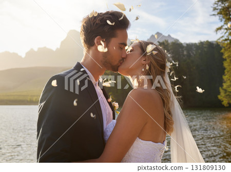 Love, wedding and confetti with a couple kissing by a lake outdoor in celebration of a marriage for romance. Water, summer or kiss with a bride and groom bonding together in tradition after ceremony Love, wedding and confetti with a couple kissing by a lake outdoor in celebration of a marriage for romance. Water, summer or kiss with a bride and groom bonding together in tradition after ceremony 131809130