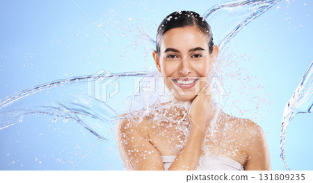 Water splash, portrait and woman shower in studio, blue background and healthy beauty of wellness skincare. Happy female model, wet and cleaning for hygiene, hydration and smile on color backdrop 131809235