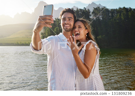 Couple, nature selfie and engagement by lake for celebration, happiness and excited for future. Man, woman and photography for social media, profile picture and romance with love, proposal and goals 131809236