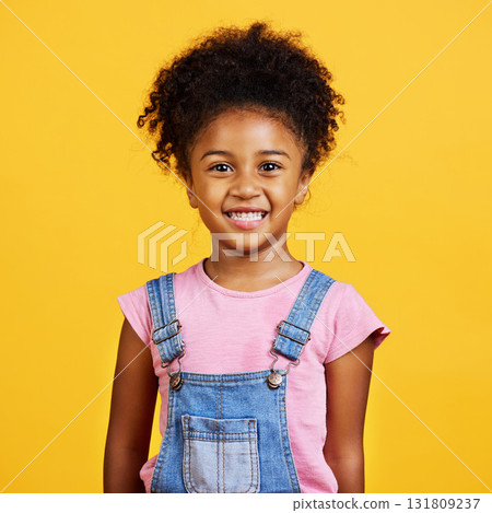 Studio portrait mixed race girl looking standing alone isolated against a yellow background. Cute hispanic child posing inside. Happy and cute kid smiling and looking carefree in casual clothes 131809237