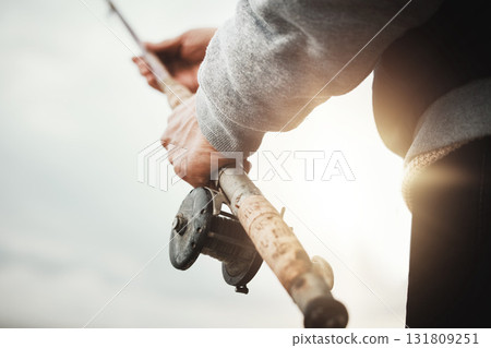 Hands, fishing and rod with a man in nature, enjoying a weekend trip his hobby or pastime at sunset. Morning, flare and low angle with a male fisherman casting a line outdoor in the wilderness Hands, fishing and rod with a man in nature, enjoying a weekend trip his hobby or pastime at sunset. Morning, flare and low angle with a male fisherman casting a line outdoor in the wilderness 131809251
