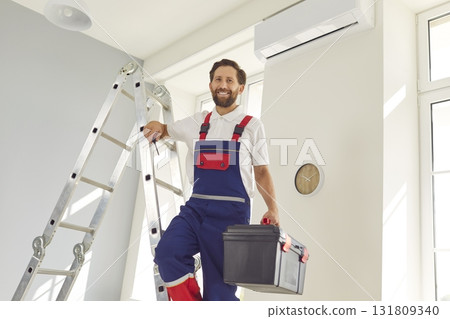Portrait of electrician with screwdriver looking at camera and smiling maintaining air conditioner 131809340