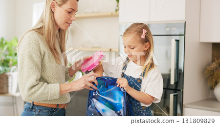 Backpack, home and mother with girl for school, education and ready for morning class in kitchen. Happy family, parents and mom with child prepare lunch, snack and books in bag for childhood learning 131809829