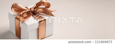 Elegant White Gift Box With a Brown Satin Ribbon Arranged on a Neutral Background 131809873