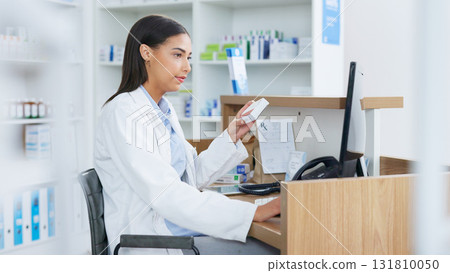 Young pharmacist working on computer at a pharmacy counter. Woman using technology to access drug database, does inventory checkup and dispensing online medicine prescriptions in a drugstore. Young pharmacist working on computer at a pharmacy counter. Woman using technology to access drug database, does inventory checkup and dispensing online medicine prescriptions in a drugstore. 131810050