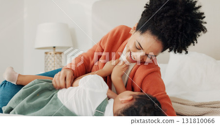 Mother, child and love in home bedroom lying in bed together for fun, tickling and laugh on family vacation. Happy African woman or parent playing with girl kid for wellness, game and holiday memory 131810066