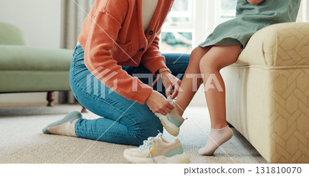 Back to school, child and mother with shoes and learning to tie shoelace in home, living room or helping with clothes in morning. Girl, mom and kid sneakers on feet for education and leaving house Back to school, child and mother with shoes and learning to tie shoelace in home, living room or helping with clothes in morning. Girl, mom and kid sneakers on feet for education and leaving house 131810070