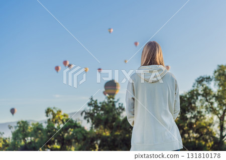 Female tourist standing with colorful hot air balloons in the sky behind her, enjoying adventure and sightseeing over Mexico. Travel, tourism, and exploration concept 131810178