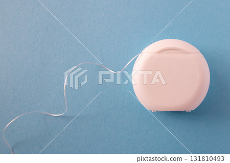 White dental floss for mouth hygiene and health teeth on blue background with space for text. White dental floss for mouth hygiene and health teeth on blue background with space for text. 131810493