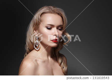 Studio portrait of a blonde model wearing statement earrings and elegant makeup, soft lighting conveying glamour, sophistication and high-end fashion appeal. Old Hollywood hair style Studio portrait of a blonde model wearing statement earrings and elegant makeup, soft lighting conveying glamour, sophistication and high-end fashion appeal. Old Hollywood hair style 131810543