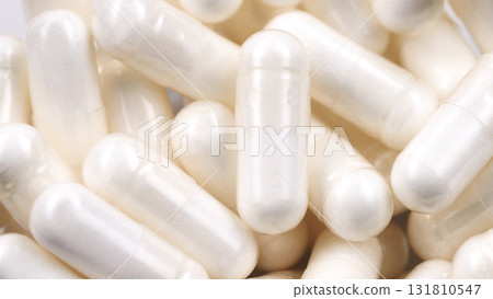 Rotating macro shot of white capsules, dietary supplements. Pharmaceutical production. Concept of medicine and healthcare. Pills and vitamins macro. Rotating macro shot of white capsules, dietary supplements. Pharmaceutical production. Concept of medicine and healthcare. Pills and vitamins macro. 131810547