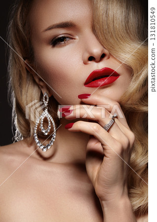 Blonde model with bold red lipstick and statement earrings. Glamour and luxury beauty style. Hollywood Diva image with red lips, classic nail manicure, old fashion wavy hairstyle and diamonds jewelry Blonde model with bold red lipstick and statement earrings. Glamour and luxury beauty style. Hollywood Diva image with red lips, classic nail manicure, old fashion wavy hairstyle and diamonds jewelry 131810549