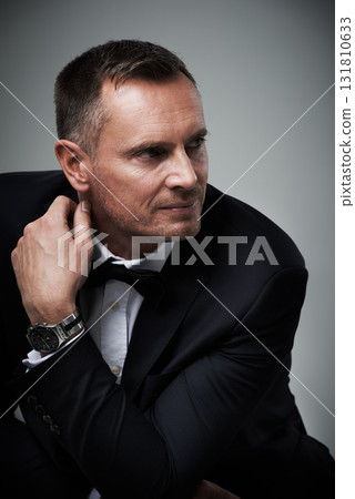 Success, handsome and mature man in tuxedo and serious and isolated on grey background in studio. Luxury, glamour and wealth with cool celebrity actor style, elegant and sexy date for valentines day. Success, handsome and mature man in tuxedo and serious and isolated on grey background in studio. Luxury, glamour and wealth with cool celebrity actor style, elegant and sexy date for valentines day. 131810633