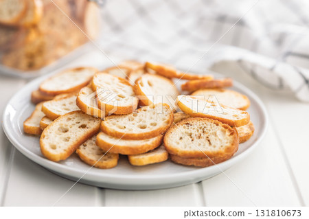 Crispy roasted bruschetta bread on plate on white table. Crispy roasted bruschetta bread on plate on white table. 131810673