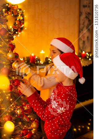 Atmospheric cozy photo of children decorating beautiful christmas tree at home. Hard-working children helping relatives and decorating living room for Christmas celebration Atmospheric cozy photo of children decorating beautiful christmas tree at home. Hard-working children helping relatives and decorating living room for Christmas celebration 131810736